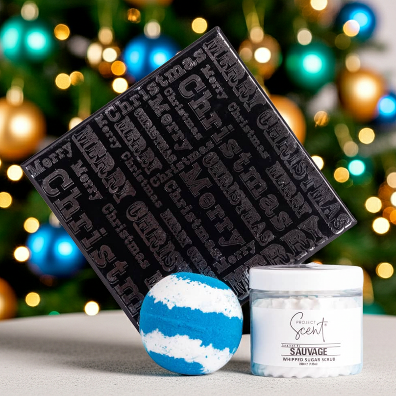 Decorative items including a black textured box, blue and white bath bomb, and a whipped sugar scrub  against a festive background.