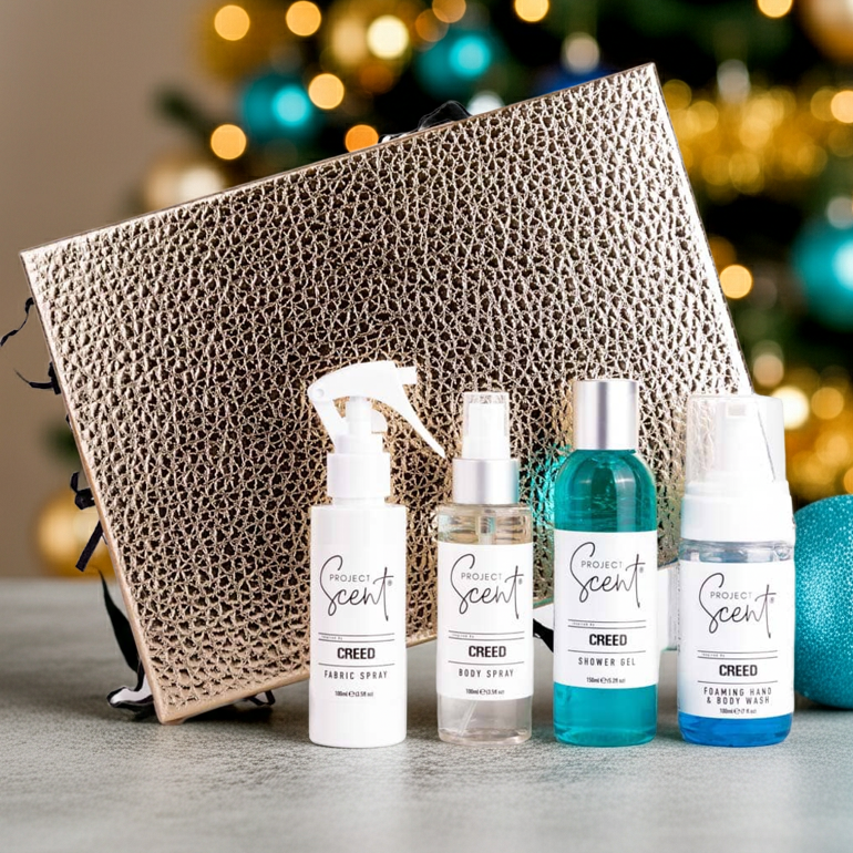 Four Creed perfume bottles with a decorative box and Christmas tree in the background