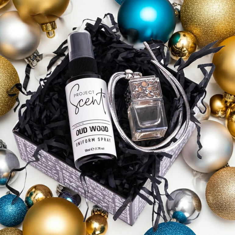 Project Scents Oud Wood perfume bottle and keychain surrounded by colorful ornaments on a white background