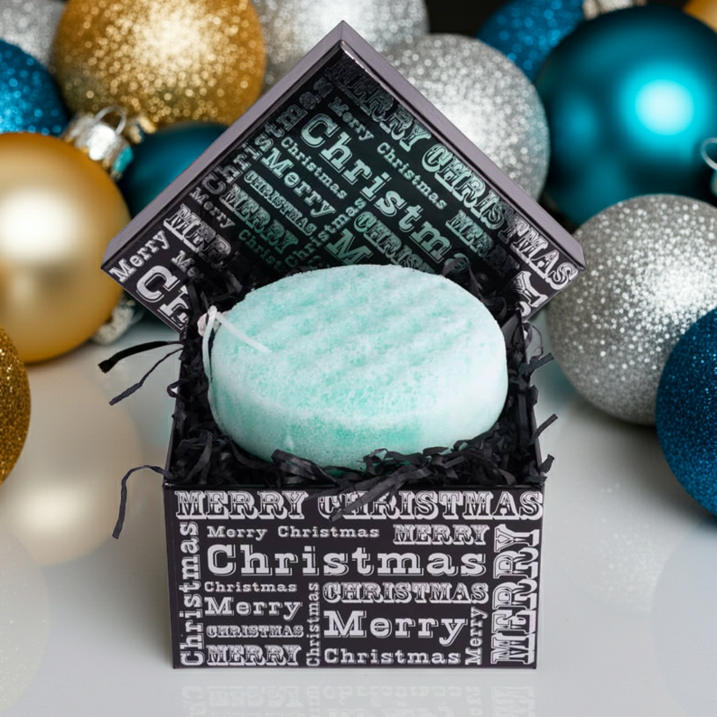 Turquoise soap sponge in a decorative box with 'Merry Christmas' text, surrounded by colorful ornaments.
