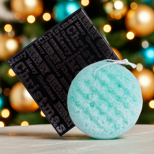 Green soap sponge with black box against a festive Christmas tree background