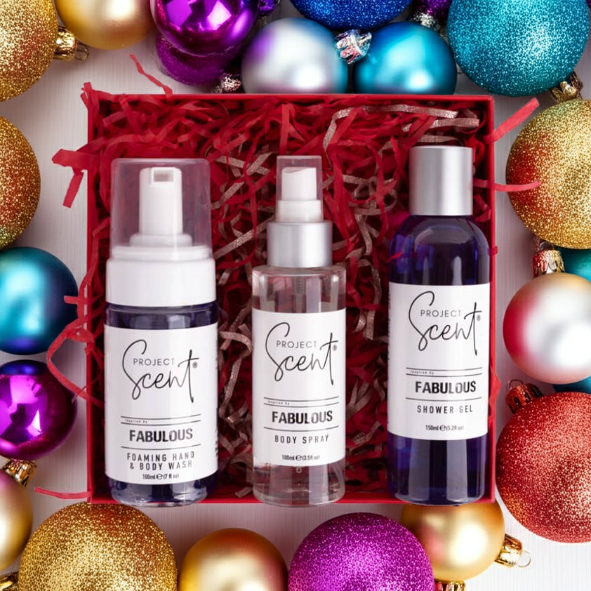 Flatlay of Christmas body care gift set surrounded by festive decorations. Features handmade shower gel, foamer and body spray gift box.