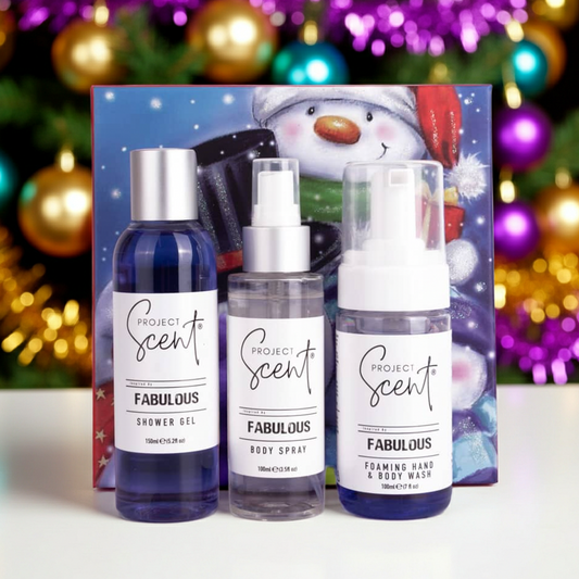 Christmas body care gift set in front of a Christmas tree. Includes handmade shower gel, foamer and body spray in festive gift packaging.