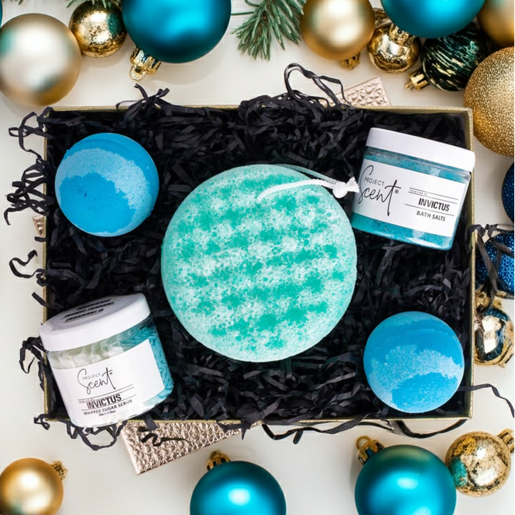 Gift set with bath bombs and jars labeled 'Invictus' surrounded by Christmas ornaments.