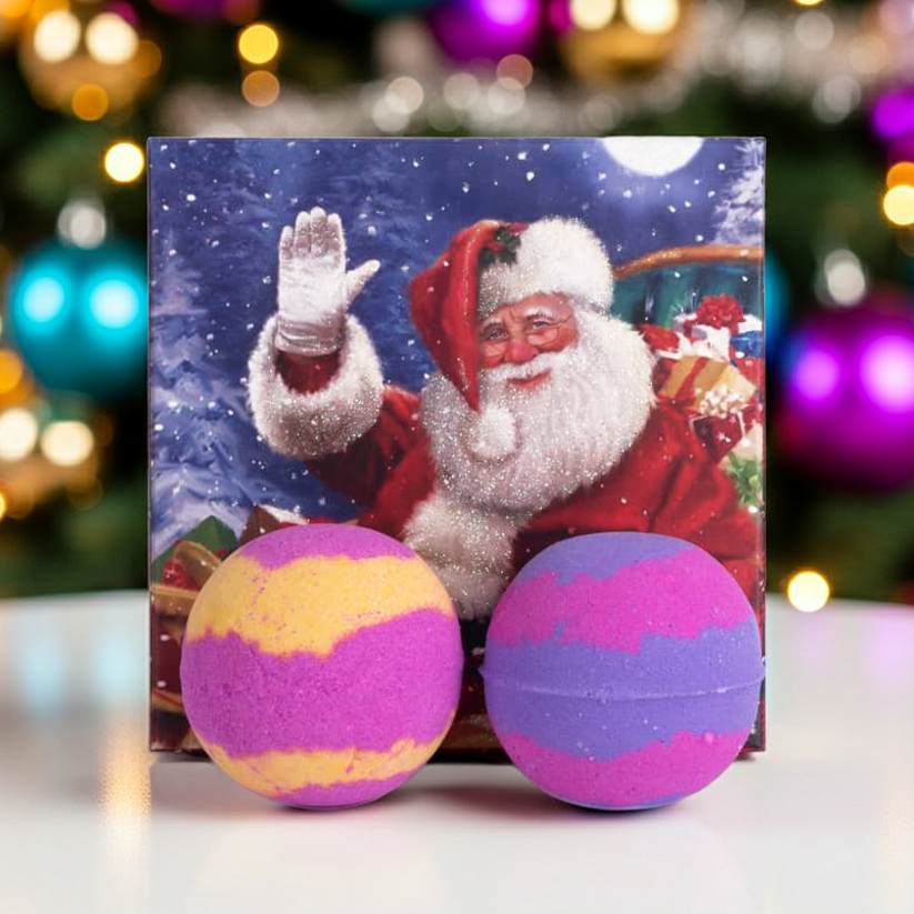Christmas bath bomb gift set displayed in front of a Christmas tree. Includes two handmade festive bath bombs in seasonal packaging.