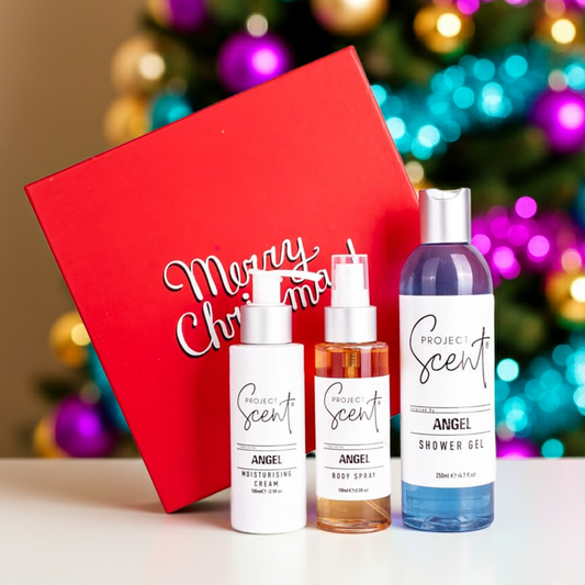 Christmas body care gift set displayed in front of a Christmas tree. Includes handmade shower gel, moisturising cream and body spray in festive packaging.
