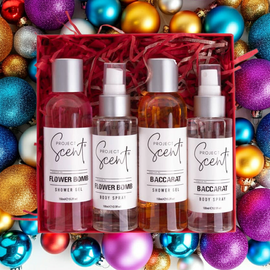 Flatlay of Christmas body care gift set surrounded by festive decorations. Features two handmade shower gels and two body sprays in gift packaging.