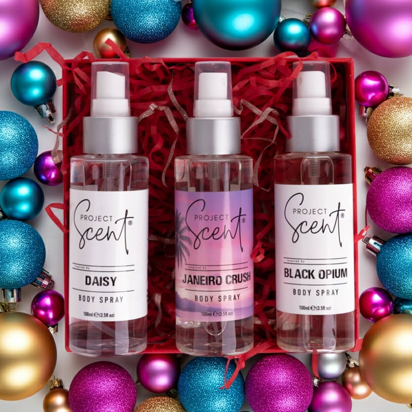 Flatlay of Christmas body spray gift set surrounded by festive decorations. Features three handmade body sprays in designer-inspired festive scents.