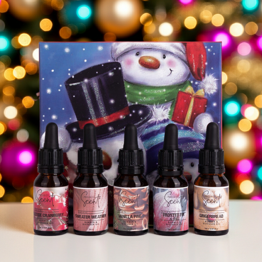 Christmas fragrance oil gift set in front of a Christmas tree. Includes five handmade diffuser and burner oils in festive packaging.