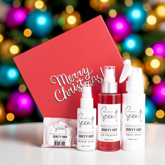 Christmas home fragrance gift set in front of a Christmas tree. Includes handmade air freshener, fabric spray, uniform spray and wax blox in festive packaging.