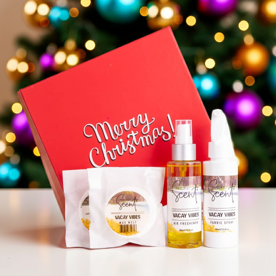 Christmas home fragrance gift set in front of a Christmas tree. Includes handmade fabric spray, air freshener and wax melts in festive packaging.