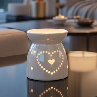 White ceramic oil burner with heart design on a coffee table in a living room.