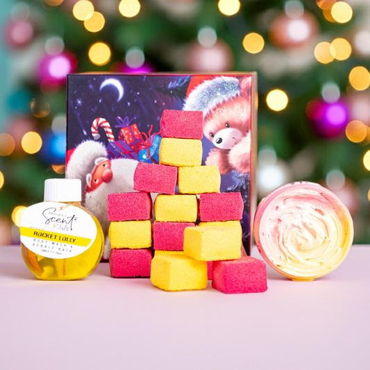 Colorful bath bomb blocks and a bottle of body wash with a Christmas-themed box in front of a decorated tree.