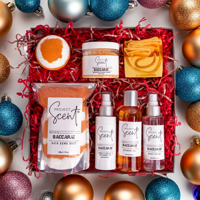 Gift set with Project Scent products surrounded by colorful Christmas ornaments on a white background