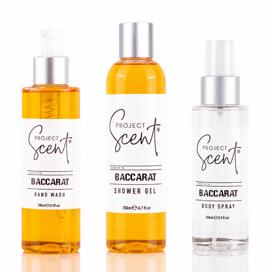 Three Project Scent Baccarat fragrance products on a white background: a hand wash bottle, a shower gel bottle, and a body spray bottle. The hand wash and shower gel contain amber-colored liquid, while the body spray is clear.