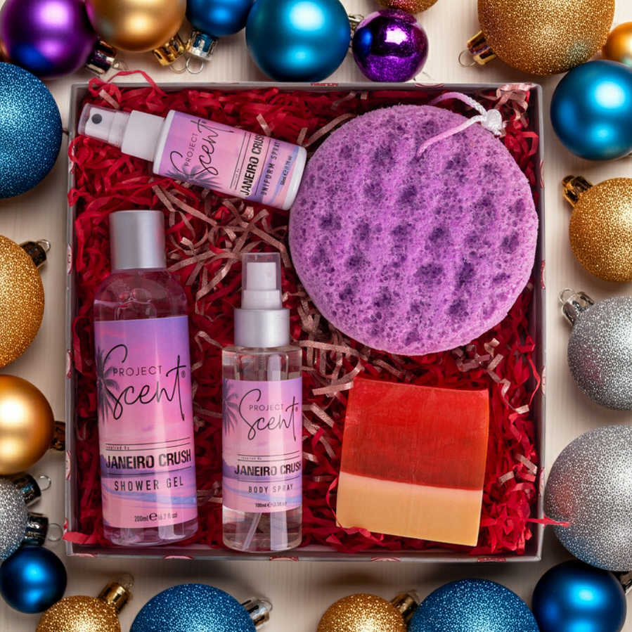 Flatlay of luxury body care gift set surrounded by Christmas decorations. Includes handmade shower gel, soap sponge, soap bar, body spray and uniform spray.