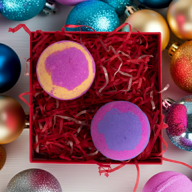 Flatlay of Christmas bath bomb gift set surrounded by festive decorations. Features two handmade bath bombs in colourful Christmas packaging.