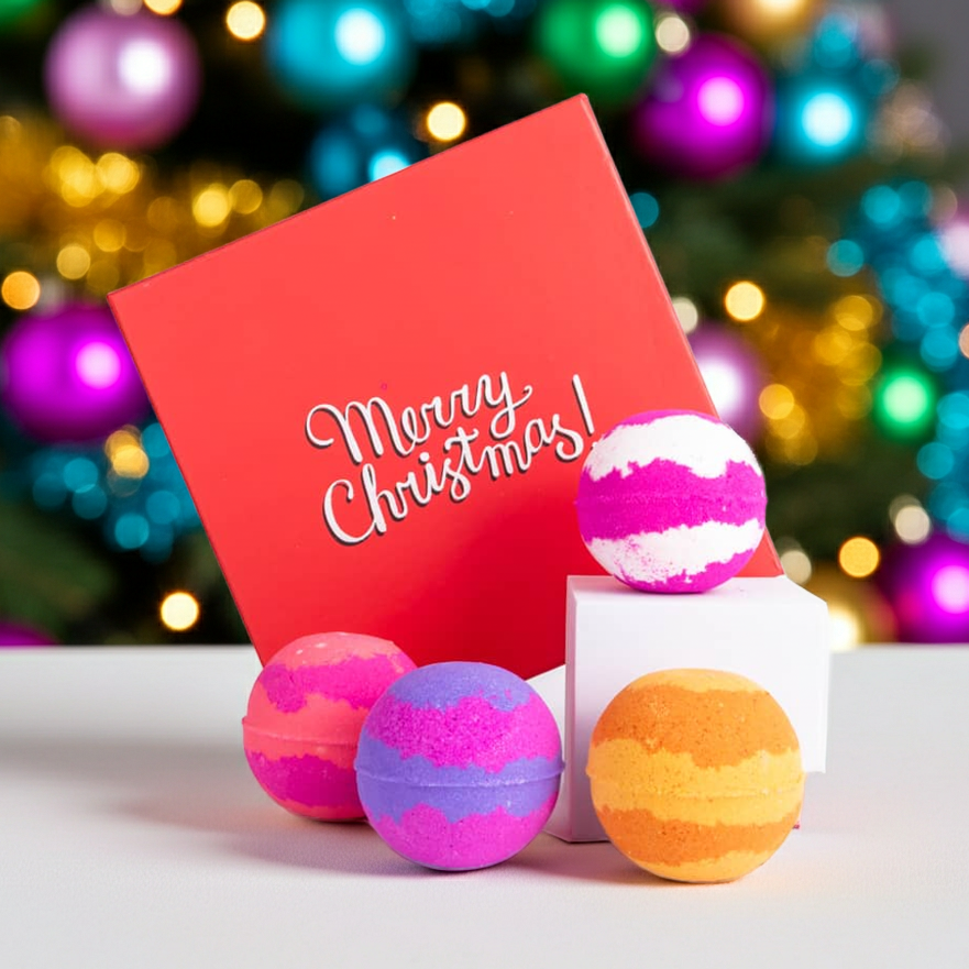 Christmas bath bomb gift set in front of a Christmas tree. Includes four handmade bath bombs in festive packaging, scented in designer-inspired fragrances.