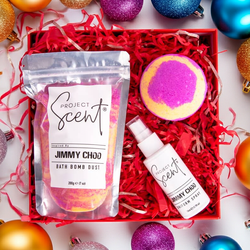 Flatlay of Christmas bath and fragrance gift set surrounded by festive decorations. Features handmade bath dust, bath bomb and uniform spray gift box.