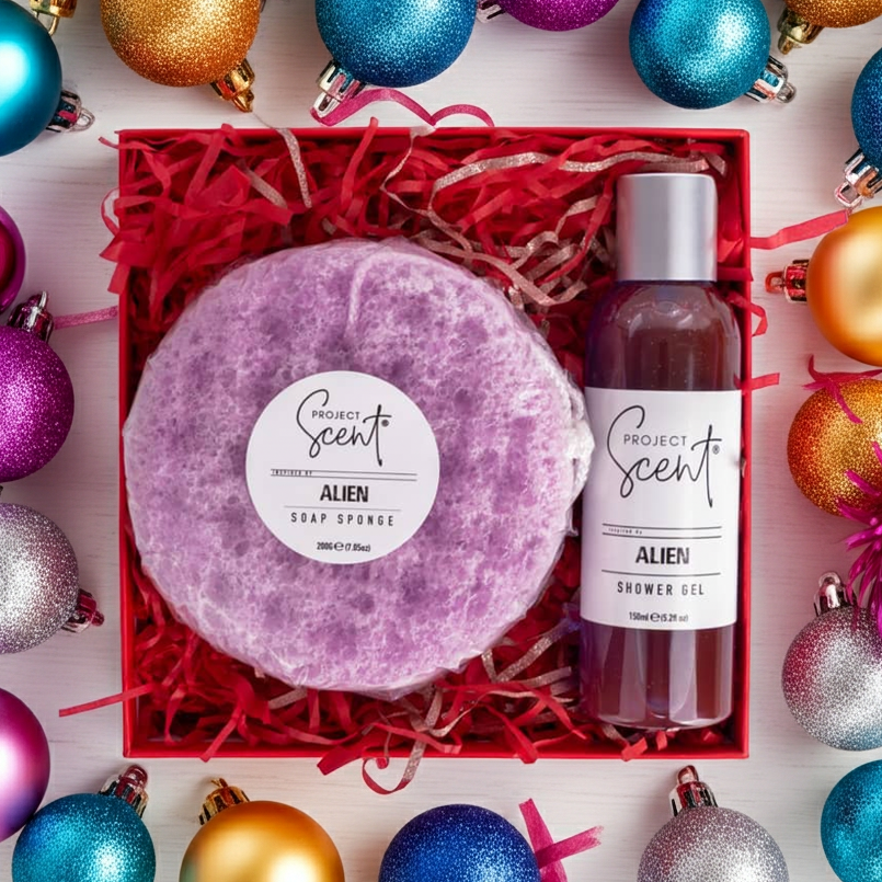 Flatlay of Christmas body care gift set surrounded by festive decorations. Features handmade shower gel and soap sponge gift box.