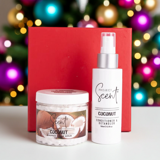 Christmas body and hair gift set in front of a Christmas tree. Includes handmade whipped sugar scrub and leave-in conditioner in festive packaging.