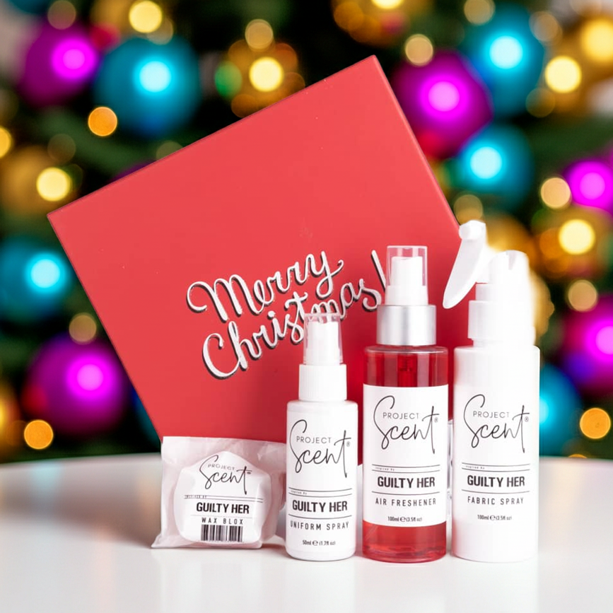 Christmas home fragrance gift set in front of a Christmas tree. Includes handmade air freshener, fabric spray, uniform spray and wax blox in festive packaging.